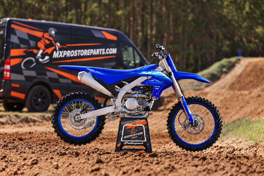 Sfeerbeeld van een Yamaha op het Polisport MXProStore-bokje met een geïllustreerde MXProStoreParts-bus op de achtergrond