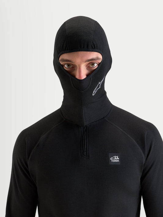 Alpinestars At 8 Merino bivakmuts, zwarte motorbivakmuts en thermische basislaag gedragen door een model, met merinomix thermische constructie en open gezichtsontwerp